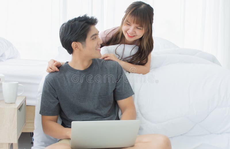 Ett par som söker internet i det vita sovrummet arkivbilder Ett par som söker internet i det vita sovrummet arkivbilder