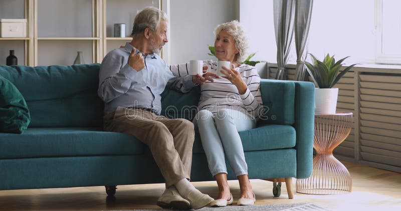 Ett pensionerat par som dricker te i vardagsrummet tillsammans stock video