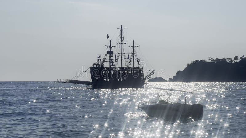 Ett piratfartyg seglar genom en solig väg till havs.