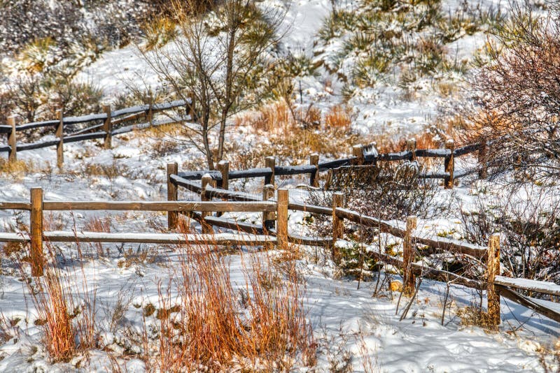 Ett pittoreskt snöig staket för ranchsplittringstång med skurar och borstar royaltyfri fotografi Ett pittoreskt snöig staket för ranchsplittringstång med skurar och borstar royaltyfri fotografi