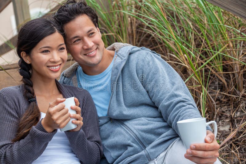 Ett romantiskt par på strandtrappor som dricker kaffe eller te