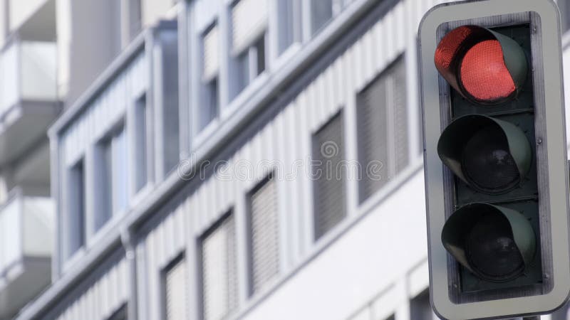Ett rött trafikljus sitter framför en byggnad