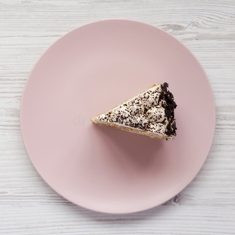 Ett stycke av tiramisukakan på en rosa platta på en vit träbakgrund, bästa sikt Lekmanna- l?genhet, ?ver huvudet, fr?n ?ver arkivbilder Ett stycke av tiramisukakan på en rosa platta på en vit träbakgrund, bästa sikt Lekmanna- l?genhet, ?ver huvudet, fr?n ?ver arkivbilder