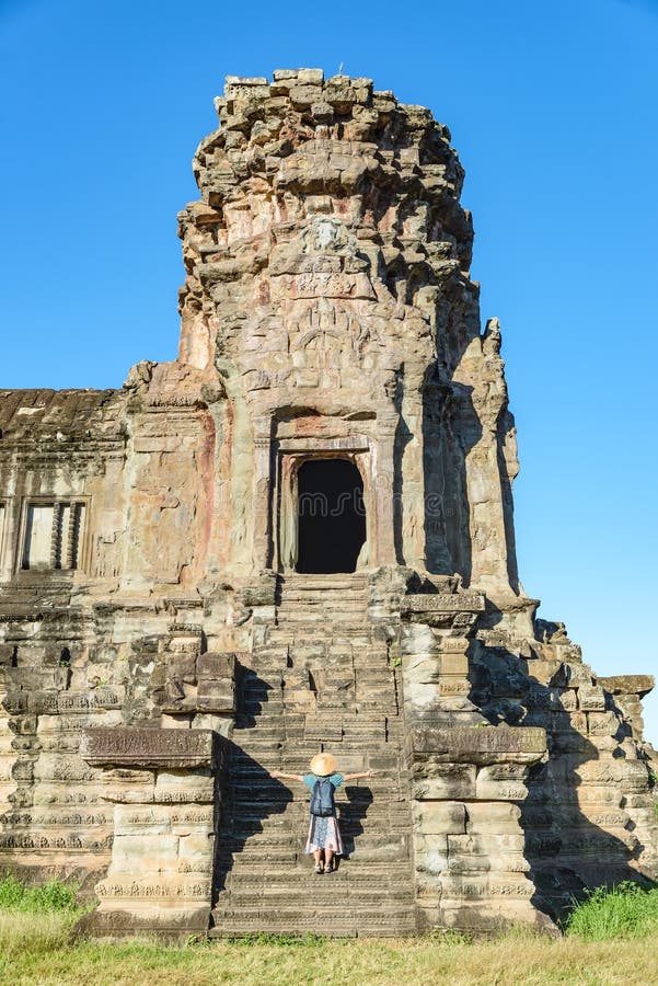 Ett turist- bes?ka Angkor Wat f?rd?rvar p? soluppg?ng, loppdestinationen Cambodja Kvinna med den traditionella hatten och lyftta royaltyfria foton Ett turist- bes?ka Angkor Wat f?rd?rvar p? soluppg?ng, loppdestinationen Cambodja Kvinna med den traditionella hatten och lyftta royaltyfria foton