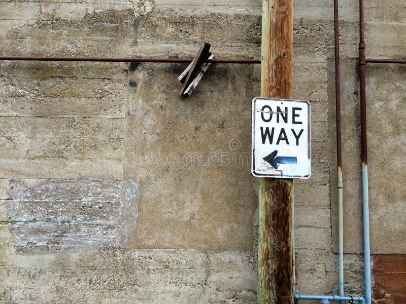 One way sign in an urban alley along an old building wall. One way sign in an urban alley along an old building wall.