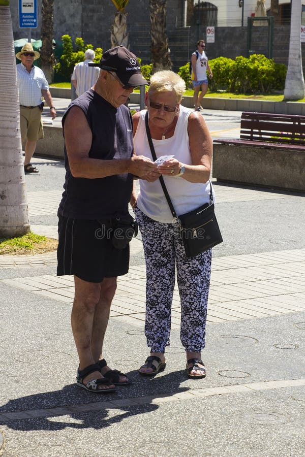 Ett äldre par kontrollerar ett kassalådakvitto på den huvudsakliga gatan av Playa Las Americas i Teneriffe arkivbilder Ett äldre par kontrollerar ett kassalådakvitto på den huvudsakliga gatan av Playa Las Americas i Teneriffe arkivbilder