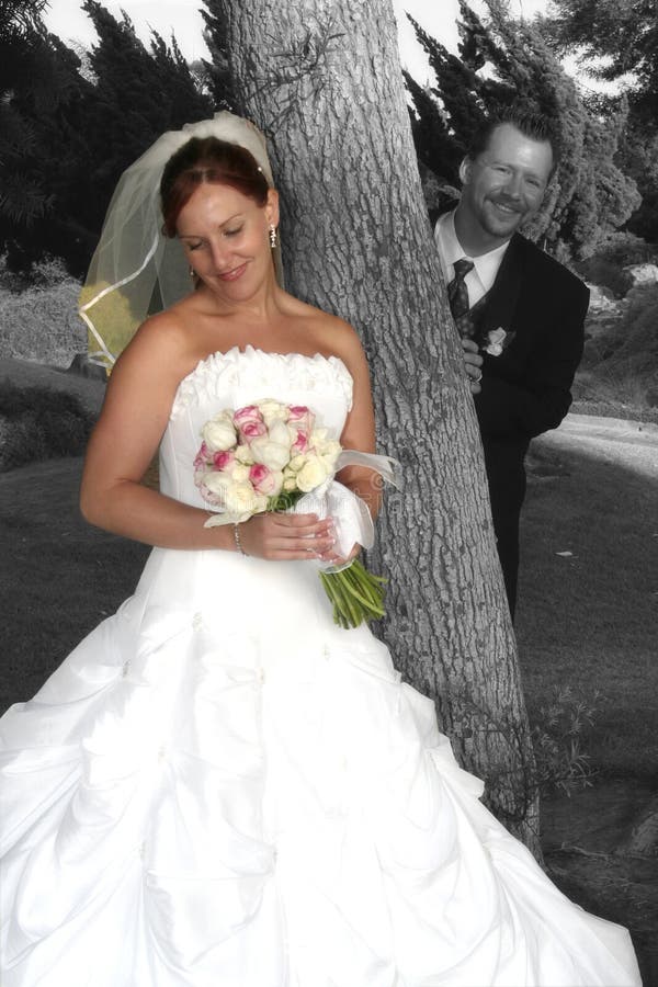 Bride poses for photo while groom looks on. Bride poses for photo while groom looks on