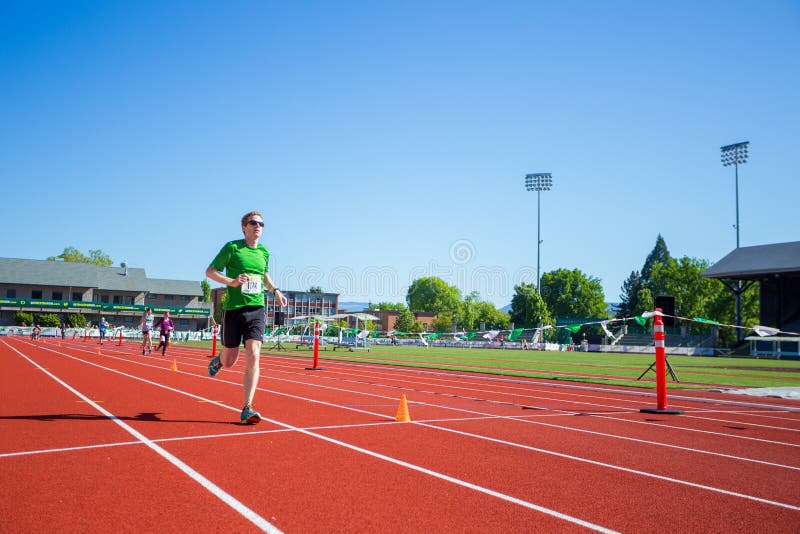 EUGENE, LUB - MAJ 1, 2016: Biegacz zbliża się metę na śladzie przy Hayward polem podczas 2016 Eugene maratonu, Boston kwalifikacyjny wydarzenie