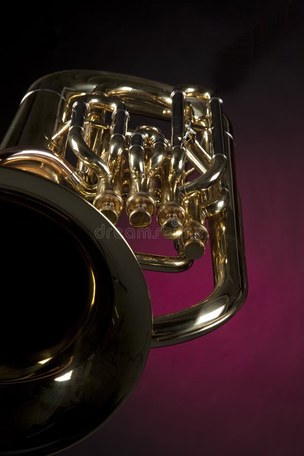 A gold brass tuba euphonium baritone horn isolated against a spotlight red background. A gold brass tuba euphonium baritone horn isolated against a spotlight red background.