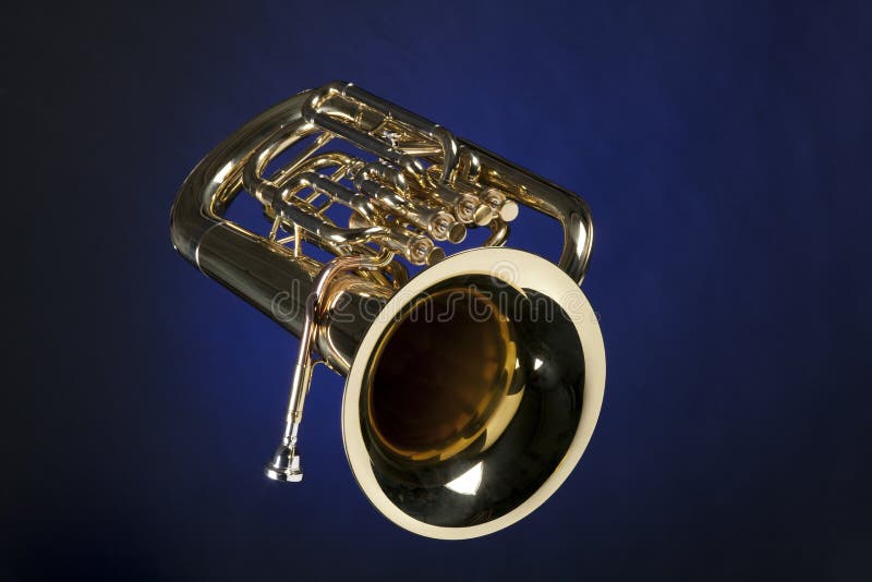 A gold brass euphonium tuba baritone horn isolated against a blue background. A gold brass euphonium tuba baritone horn isolated against a blue background.