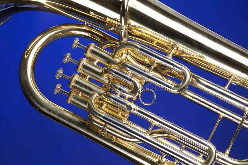 A gold brass tuba euphonium baritone horn isolated against a blue background in the horizontal format. A gold brass tuba euphonium baritone horn isolated against a blue background in the horizontal format.