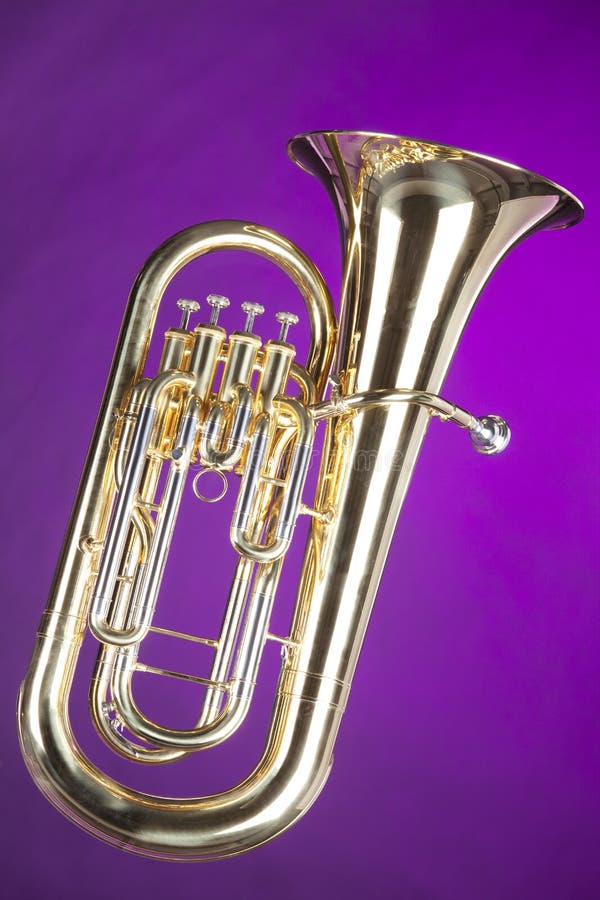 A gold brass tuba euphonium baritone horn isolated against a spotlight purple background in the vertical format. A gold brass tuba euphonium baritone horn isolated against a spotlight purple background in the vertical format