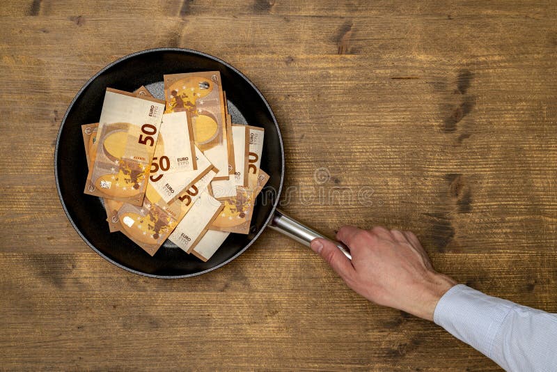 Euro bills in a frying pan on wooden  background