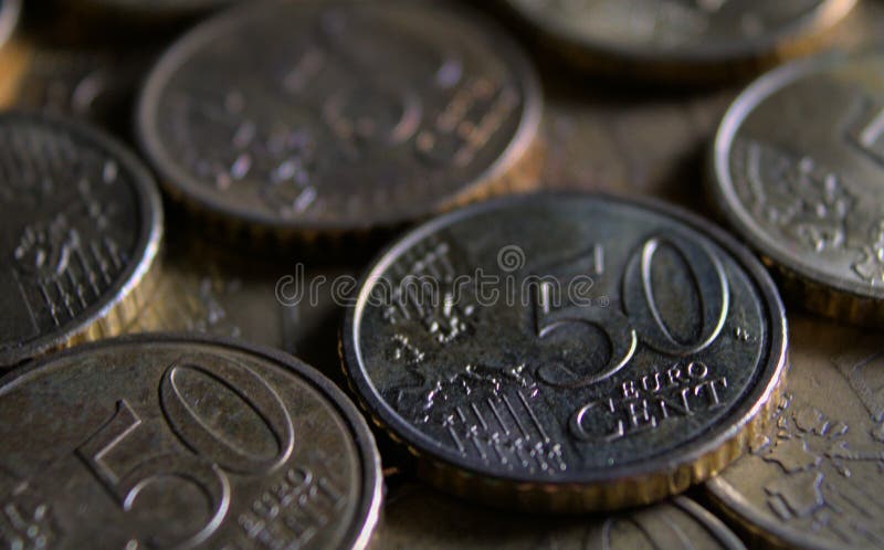 50 euro cent coin lying in a row of coins. Macro photography in dark tones. The rows of coins are angled towards the bottom of the photograph. Can also be used as a pattern or background.