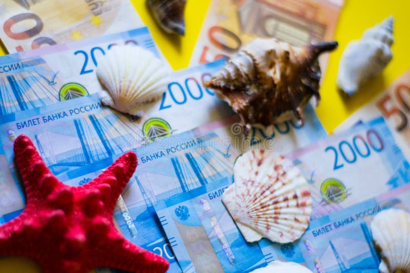 Euro och rubel med röda och vita snäckskal på gul backgrong royaltyfri bild Euro och rubel med röda och vita snäckskal på gul backgrong royaltyfri bild
