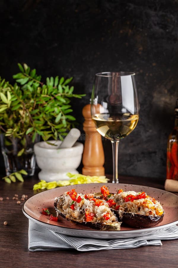 European Spanish cuisine. Baked eggplants with meat and vegetables, parmesan cheese. White wine on the table. Close-up background