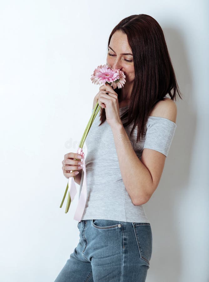 European, young brown-haired woman in a grey top and jeans with pink flowers, gerberas, portrait of a girl royalty free stock photography European, young brown-haired woman in a grey top and jeans with pink flowers, gerberas, portrait of a girl royalty free stock photography