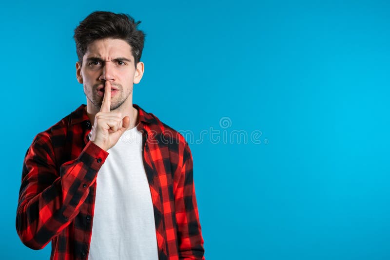 European handsome man holding finger on his lips over blue background. Gesture of shhh, secret, silence. European handsome man holding finger on his lips over blue background. Gesture of shhh, secret, silence.