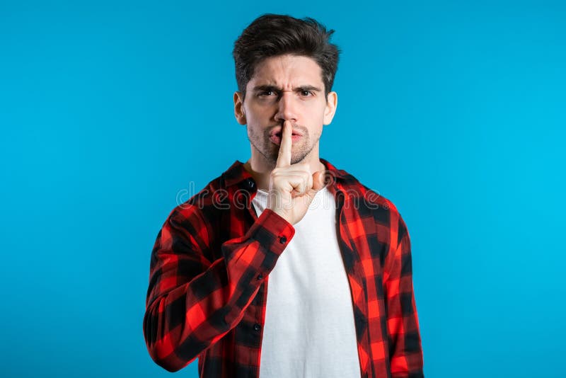 European handsome man holding finger on his lips over blue background. Gesture of shhh, secret, silence. European handsome man holding finger on his lips over blue background. Gesture of shhh, secret, silence.