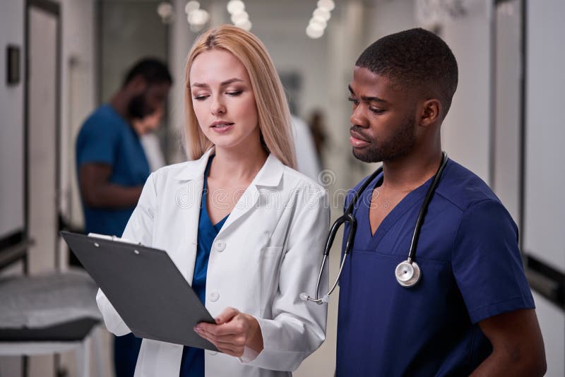 Europäische Berufsdoktorfrau, die afroen-amerikanisch Studenten gelehrt, kam im Krankenhaus zu üben lizenzfreies stockbild