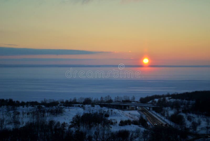 Evening panorama of the embankment of the frozen Volga River against the backdrop of a stunning sunset sky and clouds.