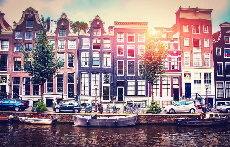 Evening sunset in Amsterdam. Amsterdam street with canals and boats against backdrop of Dutch houses