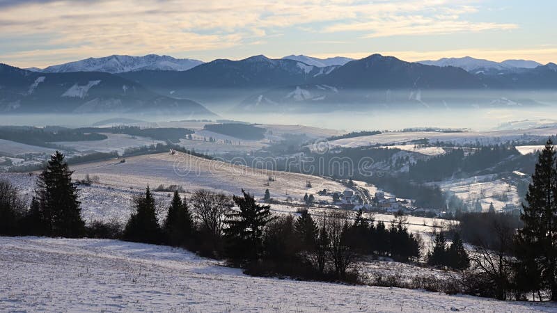 Evening winter landscape under Low Tatras mountains with some low evening fog present.