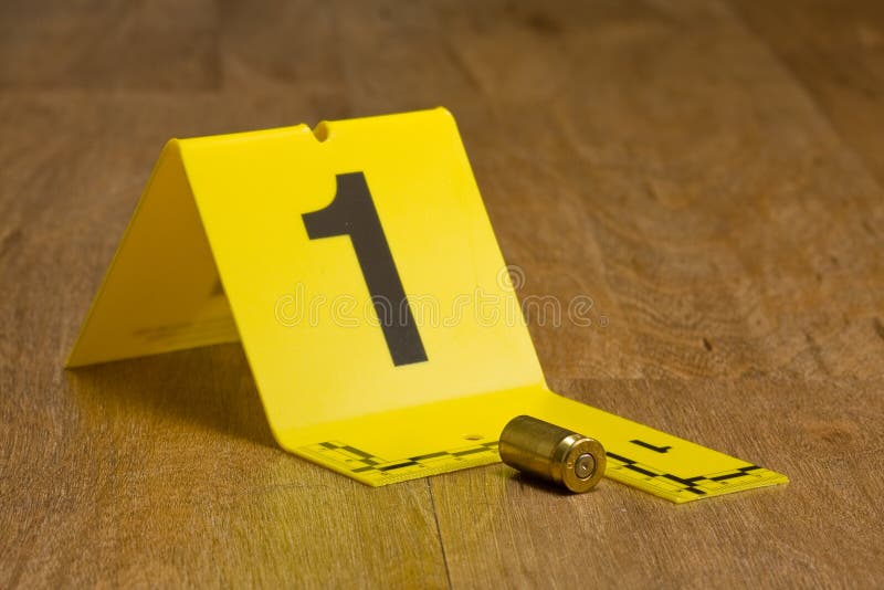 Evidence marker with bullet casing on wooden floor. Evidence marker with bullet casing on wooden floor