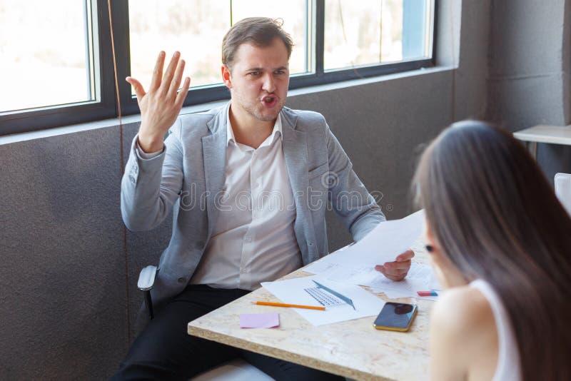 Evil male boss, aggressively shouts at his subordinate girl. Indoors in the office. stock image Evil male boss, aggressively shouts at his subordinate girl. Indoors in the office. stock image