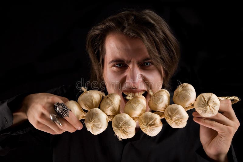 Evil vampire with scary eyes eating garlic royalty free stock image
