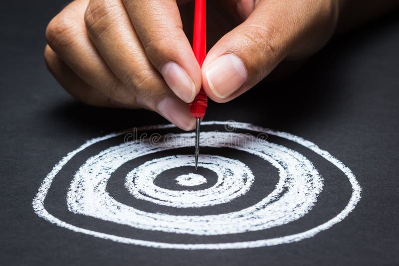 Setting goal or accurate planning, hand going to take dart into the center of sketching dartboard. Setting goal or accurate planning, hand going to take dart into the center of sketching dartboard