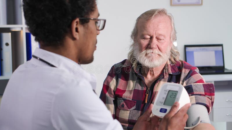 Exame médico encantando idoso na recepção de jovem profissional depois de medidas médicas americanas
