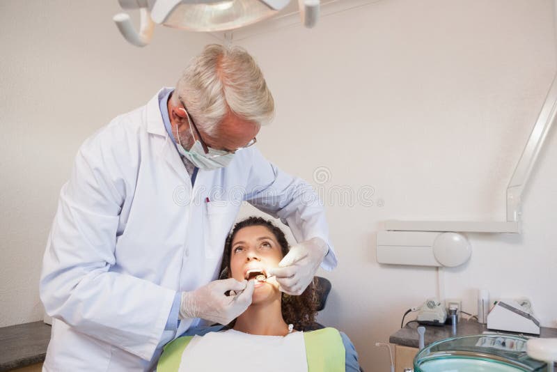 Dentist examining a patients teeth in the dentists chair at the dental clinic. Dentist examining a patients teeth in the dentists chair at the dental clinic