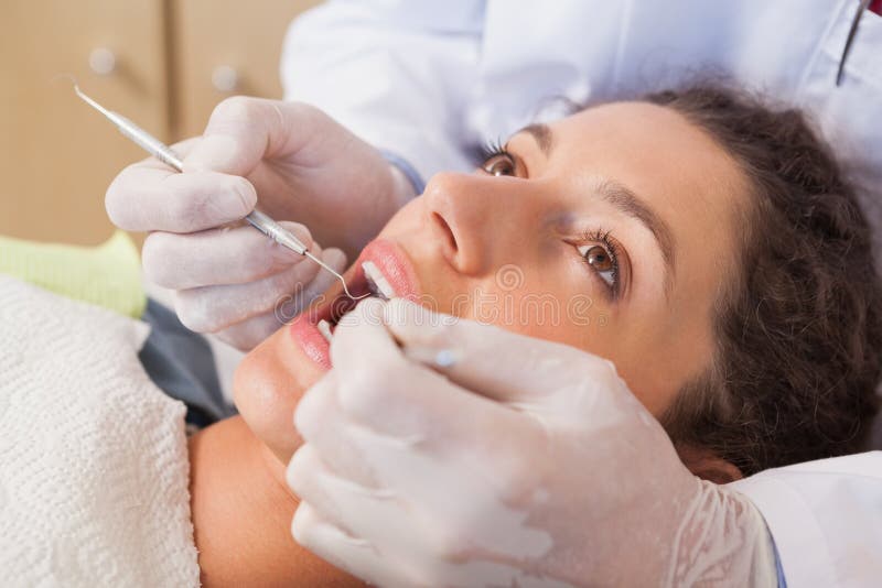 Dentist examining a patients teeth in the dentists chair at the dental clinic. Dentist examining a patients teeth in the dentists chair at the dental clinic