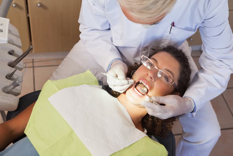 Dentist examining a patients teeth in the dentists chair at the dental clinic. Dentist examining a patients teeth in the dentists chair at the dental clinic