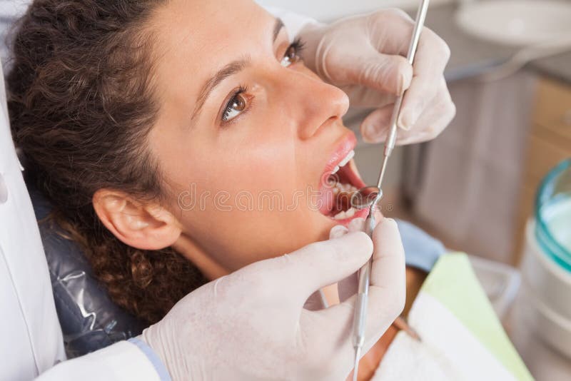 Dentist examining a patients teeth in the dentists chair at the dental clinic. Dentist examining a patients teeth in the dentists chair at the dental clinic