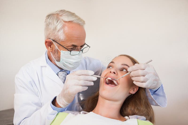 Dentist examining a patients teeth in the dentists chair at the dental clinic. Dentist examining a patients teeth in the dentists chair at the dental clinic