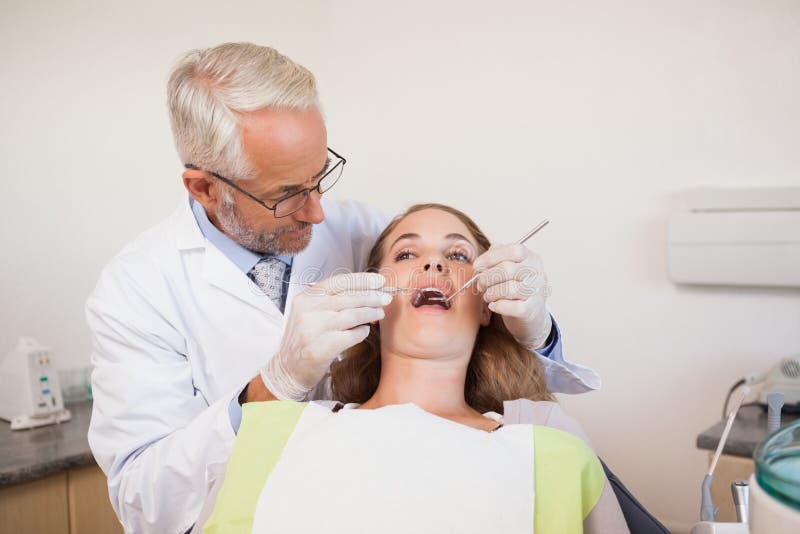 Dentist examining a patients teeth in the dentists chair at the dental clinic. Dentist examining a patients teeth in the dentists chair at the dental clinic