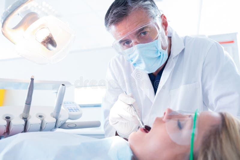 Dentist examining a patients teeth in the dentists chair at the dental clinic. Dentist examining a patients teeth in the dentists chair at the dental clinic