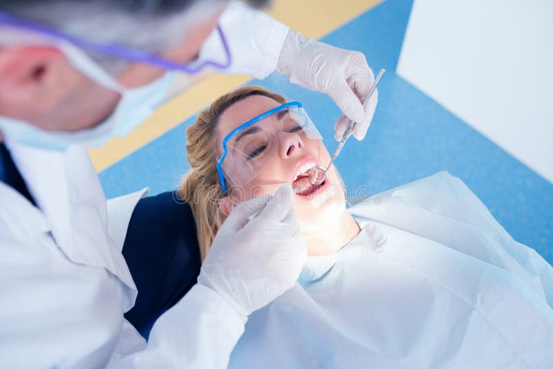 Dentist examining a patients teeth in the dentists chair at the dental clinic. Dentist examining a patients teeth in the dentists chair at the dental clinic