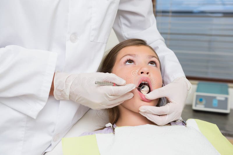 Pediatric dentist examining a little girls teeth in the dentists chair at the dental clinic. Pediatric dentist examining a little girls teeth in the dentists chair at the dental clinic