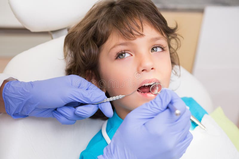 Pediatric dentist examining a little boys teeth in the dentists chair at the dental clinic. Pediatric dentist examining a little boys teeth in the dentists chair at the dental clinic