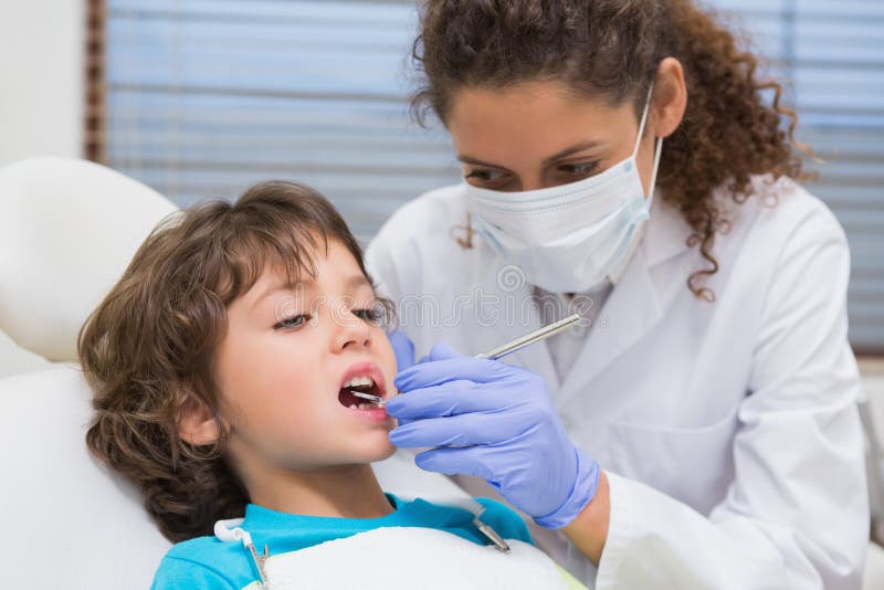 Pediatric dentist examining a little boys teeth in the dentists chair at the dental clinic. Pediatric dentist examining a little boys teeth in the dentists chair at the dental clinic