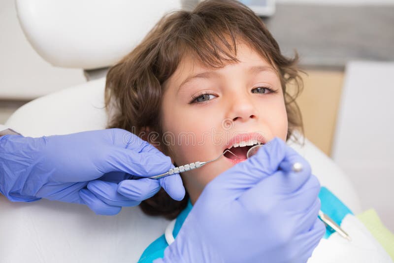 Pediatric dentist examining a little boys teeth in the dentists chair at the dental clinic. Pediatric dentist examining a little boys teeth in the dentists chair at the dental clinic