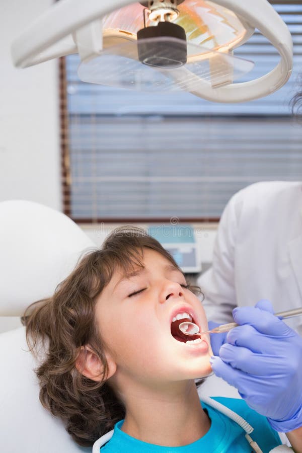 Pediatric dentist examining a little boys teeth in the dentists chair at the dental clinic. Pediatric dentist examining a little boys teeth in the dentists chair at the dental clinic