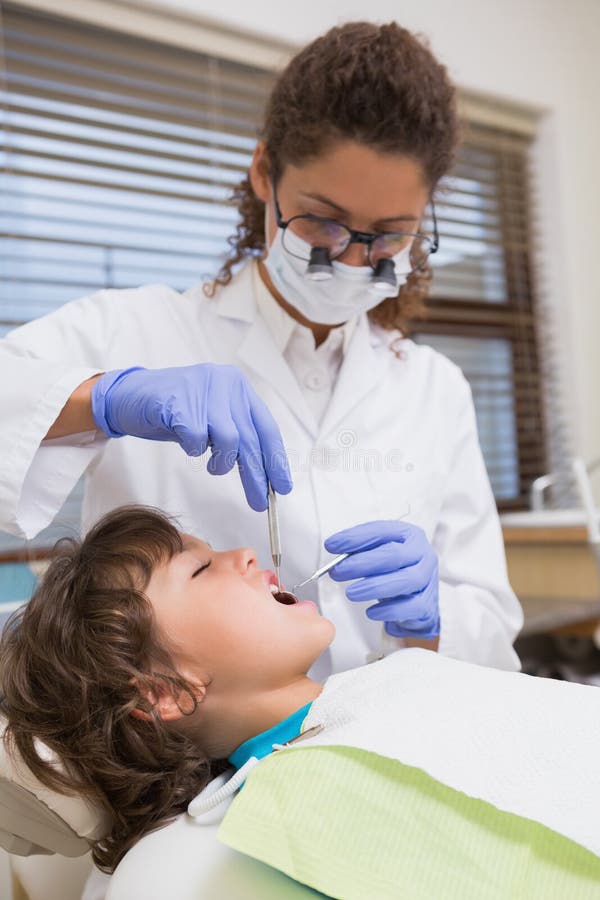 Pediatric dentist examining a little boys teeth in the dentists chair at the dental clinic. Pediatric dentist examining a little boys teeth in the dentists chair at the dental clinic