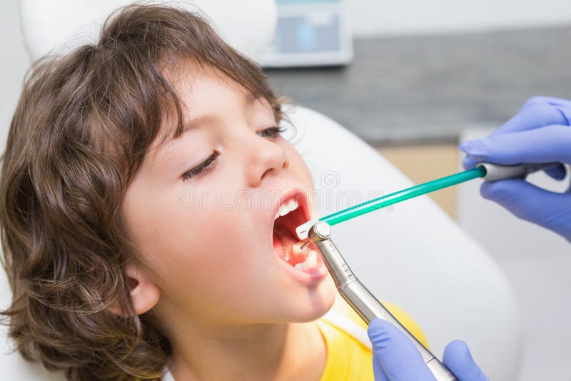 Pediatric dentist examining a little boys teeth in the dentists chair at the dental clinic. Pediatric dentist examining a little boys teeth in the dentists chair at the dental clinic