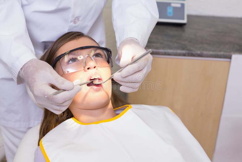 Pediatric dentist examining a patients teeth in the dentists chair at the dental clinic. Pediatric dentist examining a patients teeth in the dentists chair at the dental clinic