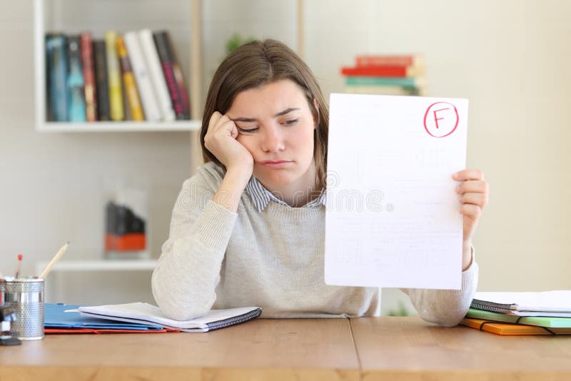 Sad student showing a failed exam to camera at home. Sad student showing a failed exam to camera at home