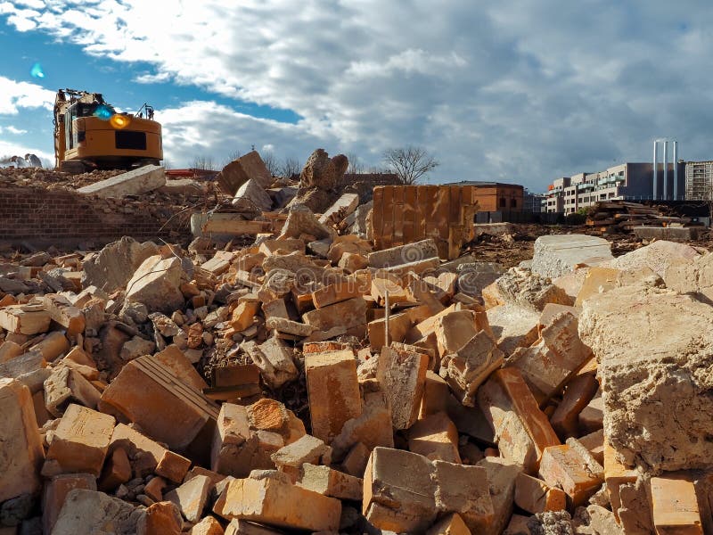 An Excavator Breaks Down An Old Building. Dust, Bricks And Broken Walls